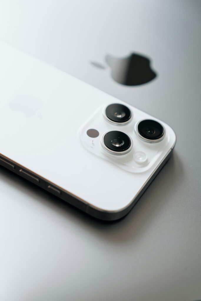 White smartphone with triple cameras lies atop a sleek laptop.