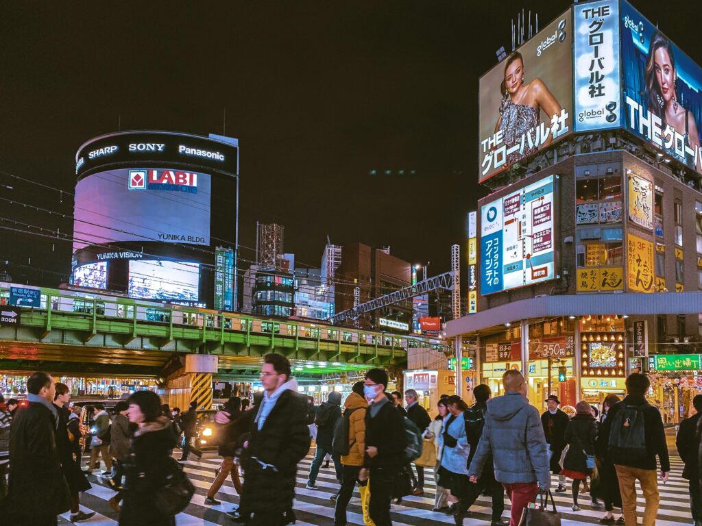 Busy night at Shibuya Crossing, Tokyo, featuring vibrant crowds and towering billboards.