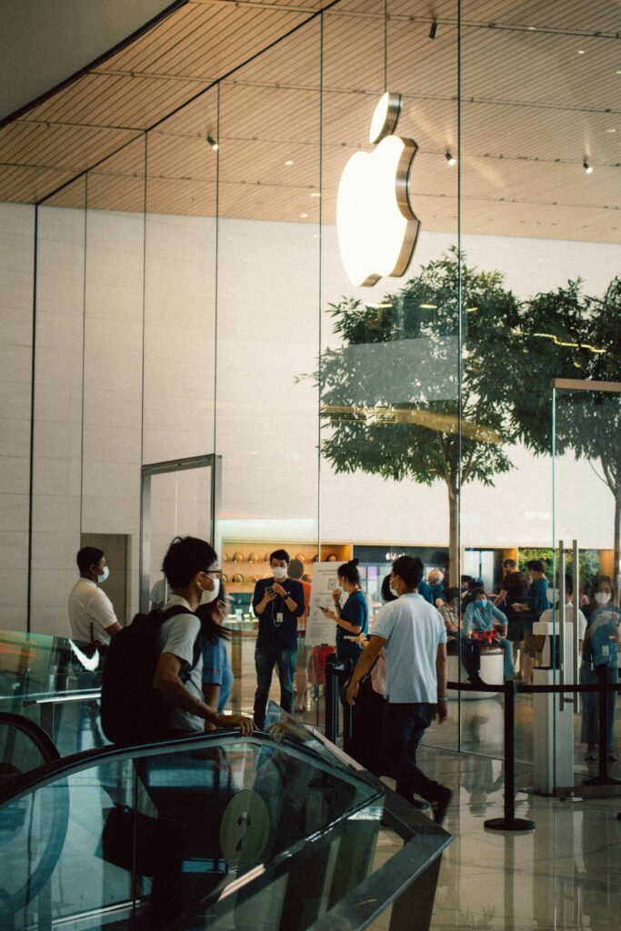 People shopping at an Apple store inside a Bangkok mall, showcasing modern retail design.